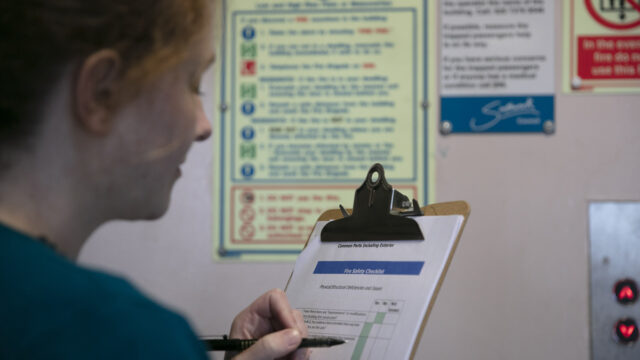 A woman holding a clipboard and looking at fire safety signs. Image by Professor Paul Wenham-Clarke